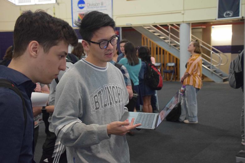 student holding laptop and talking at ACURA fair 2023