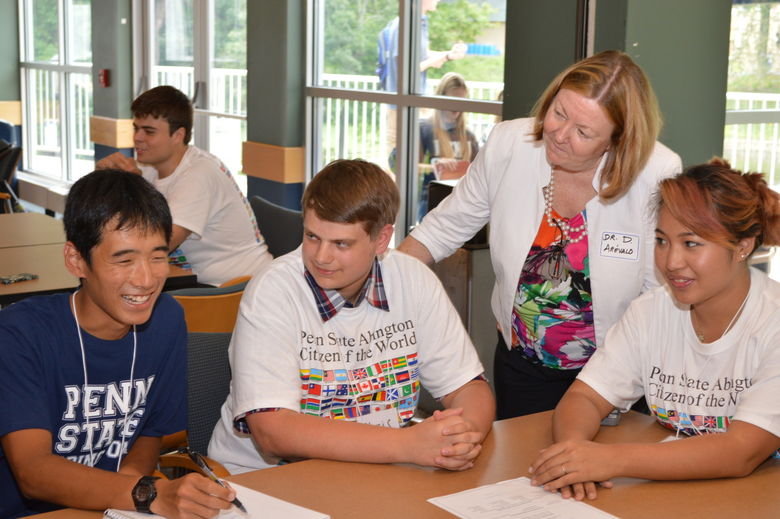 students and global programs coordinator smiling and talking by a desk