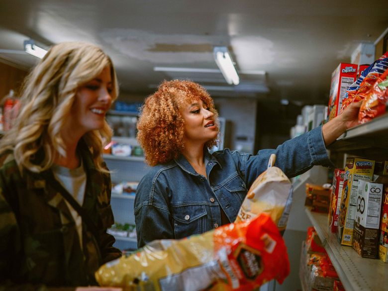 Two students picking food up off a shelf