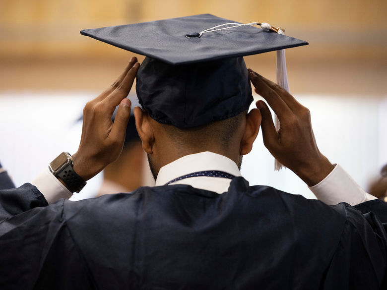 student putting on grad cap on their head