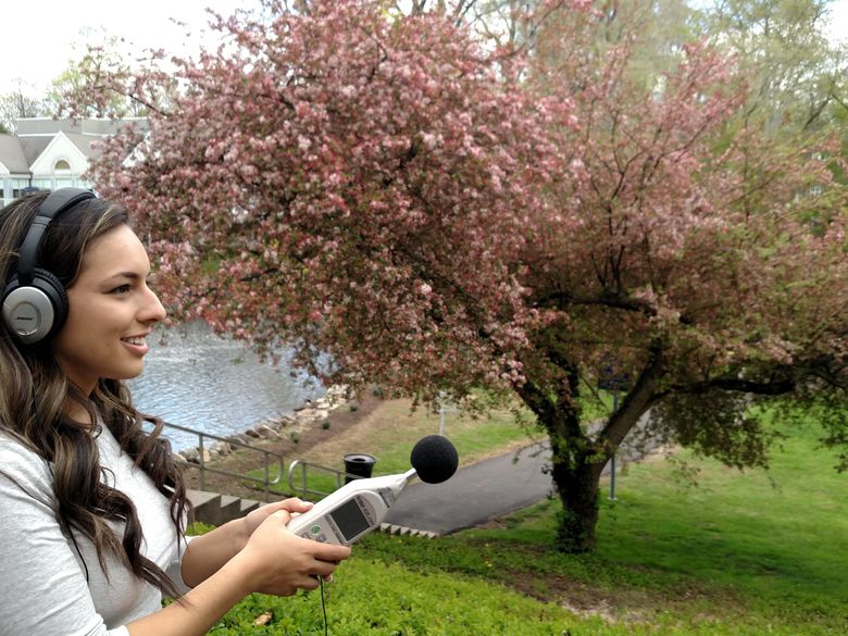 Student doing research in front of woodland facing the duck pond