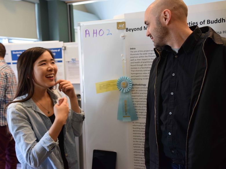 two students talking in front of poster board