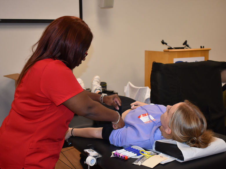 student laying on table about to get blood taken