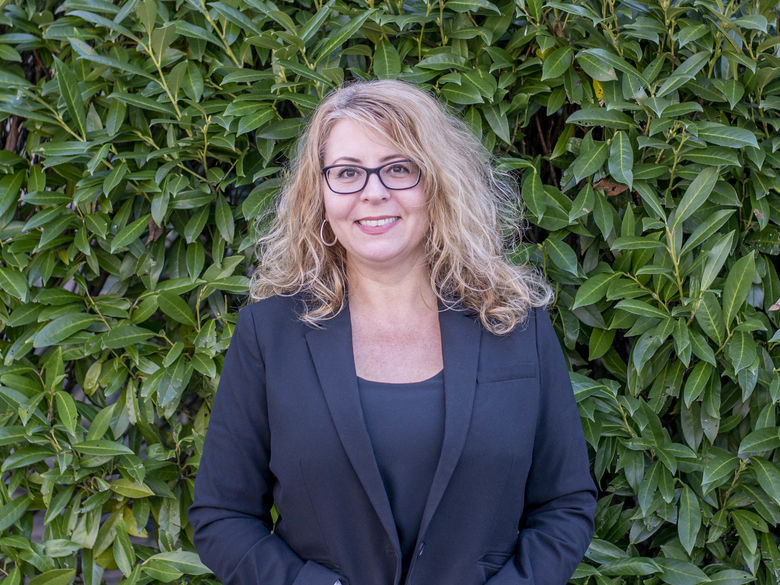 Margo DelliCarpini standing in front of bushes