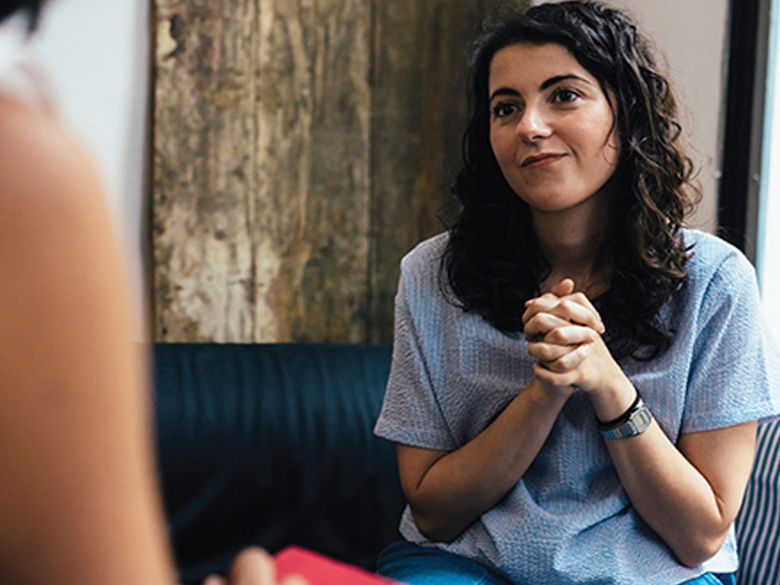 a woman holding her hands talking looking at a person she is talking to