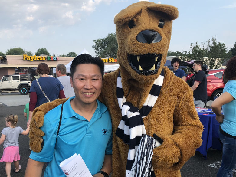 An adult standing with the Nittany Lion for a photo