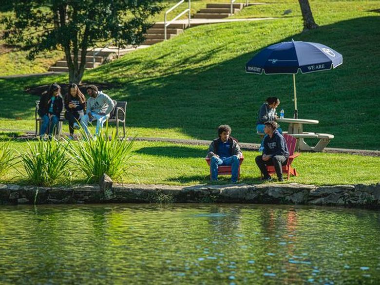 Students sit by the Lares Pond