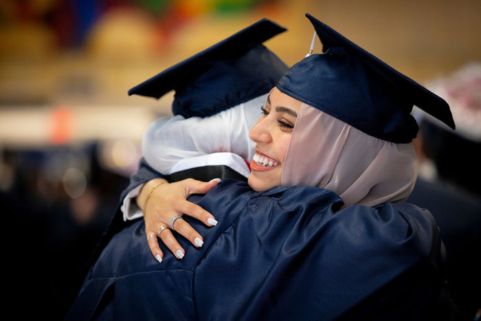 two students hugging in their caps and gowns