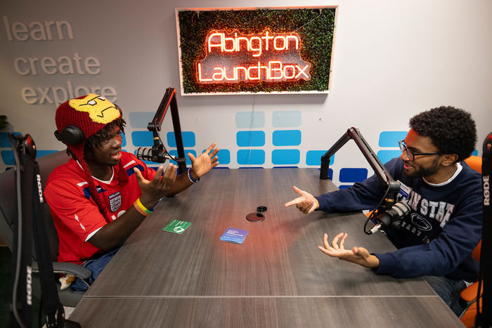 Two students during their podcast at a table with mics