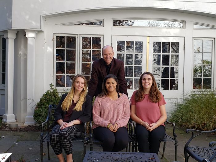 Three students and Paul Perreault in front of the Nittany Lion Inn
