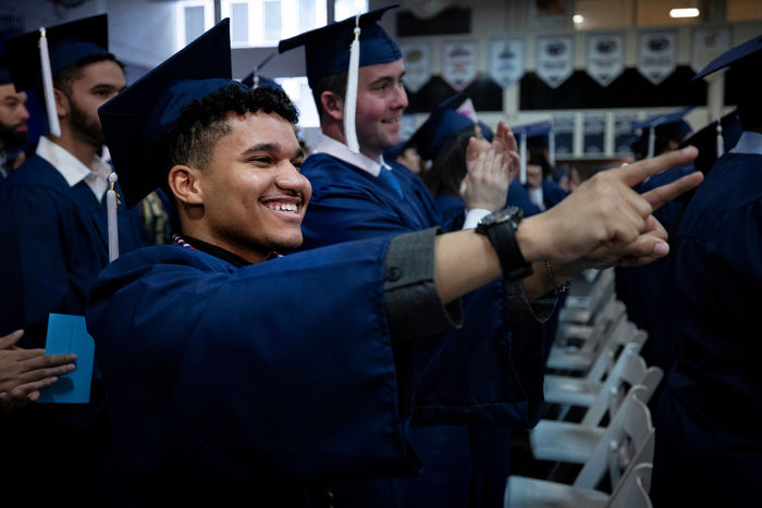 man in cap and gown pointing