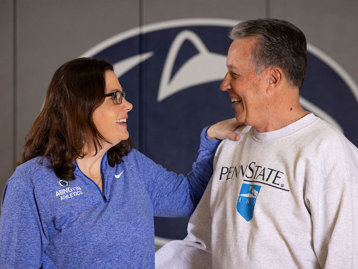 Woman and man talking in front of Penn State athletics logo