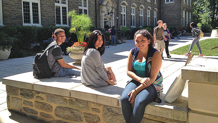 three students sitting in front of Sutherland bldg