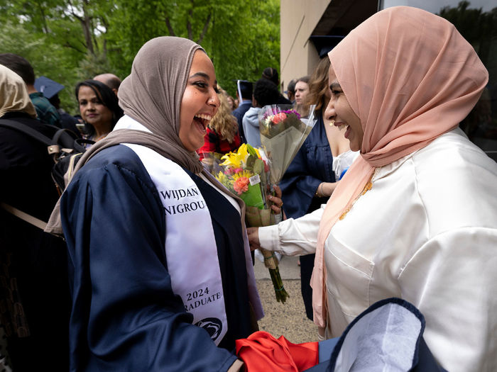 Two women celebrate after graduate ceremonies
