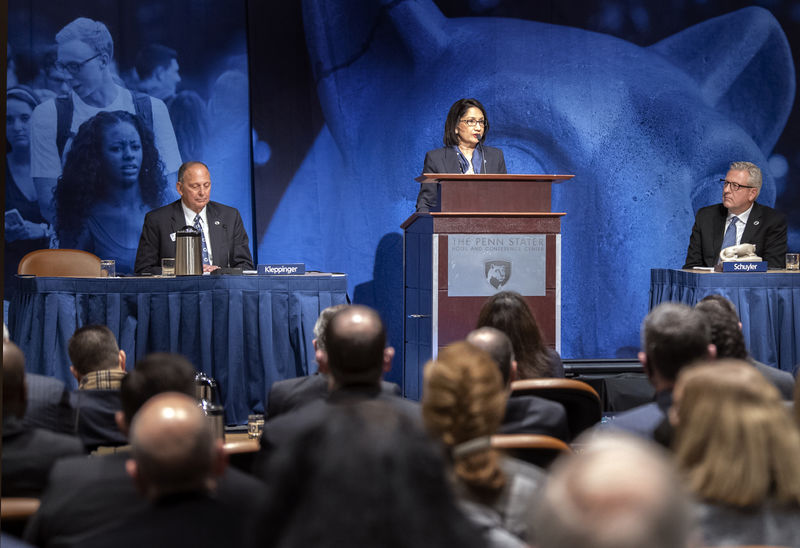 Bendapudi at podium on stage flanked by two trustees