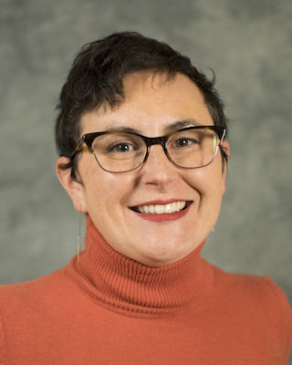 photo portrait of woman wearing black glasses and orange sweater