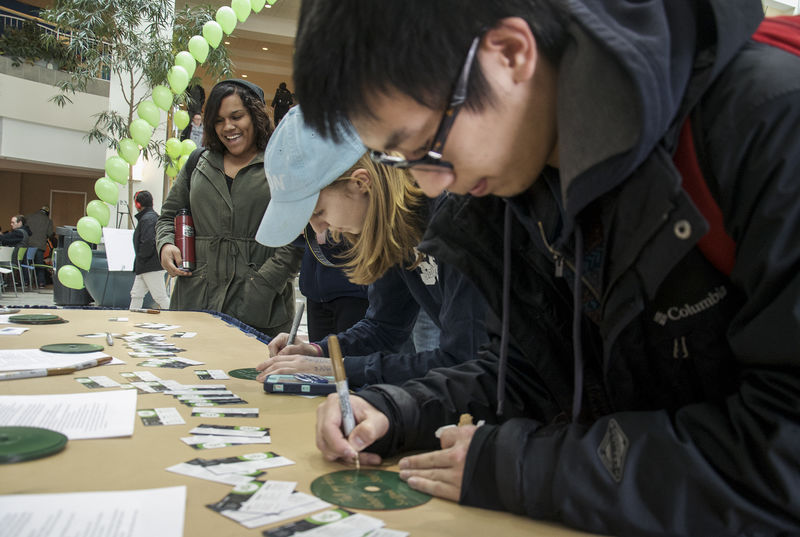 Students writing down messages on green CDs