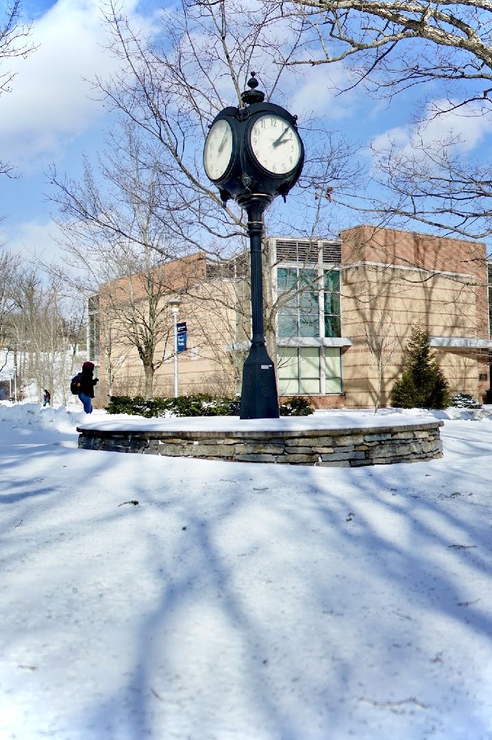 A clock tower on a sunny day with snow on the ground