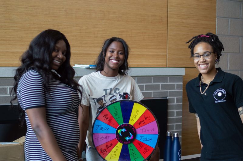 students smiling for photo with spinning wheel
