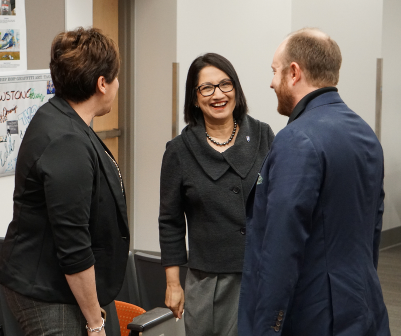 Woman laughing and smiling while standing beside a man and woman.