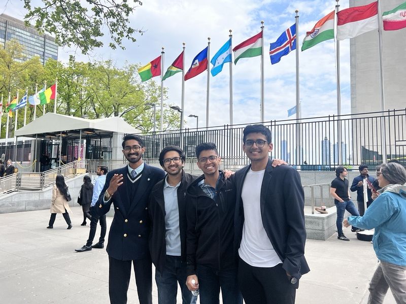 four students smiling in front of flags