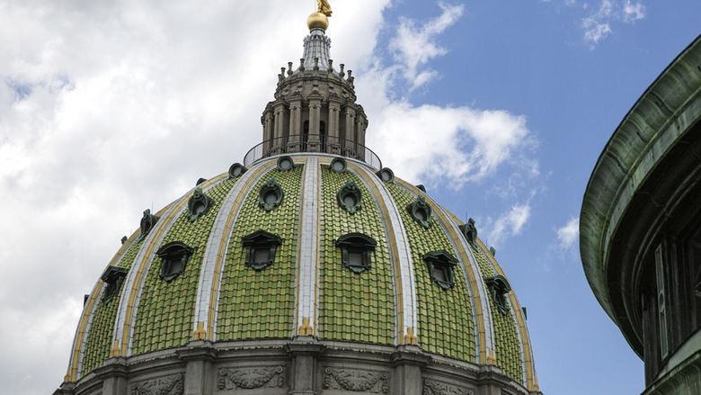 The green and gold exterior of the Pennsylvania Capitol dome against a blue sky with white clouds.
