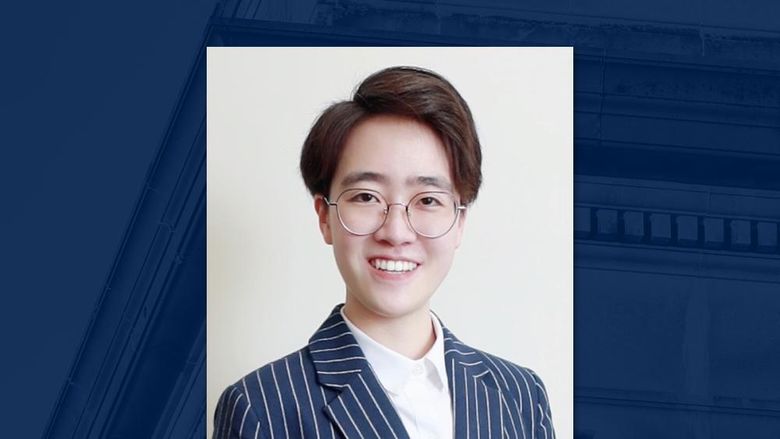 A headshot of a person wearing glasses on a blue background.