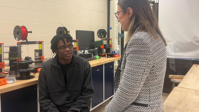 A student and a teacher talk together in a lab.