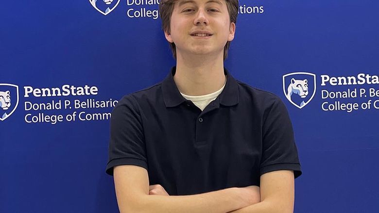 A student smiling with arms crossed