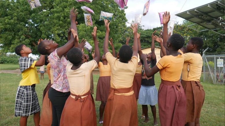 Students in Ghana throw period products in the air