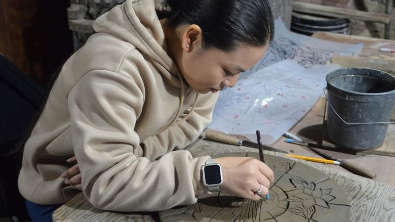 Student creating a ceramic tile
