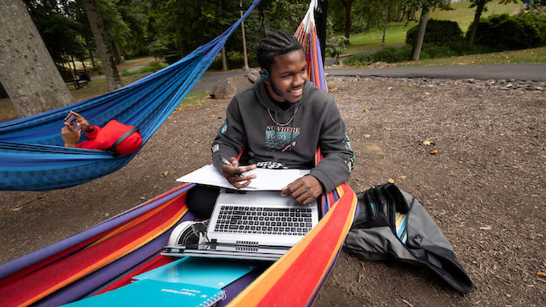 Student working on summer classes homework from Penn State Abington in a hammock