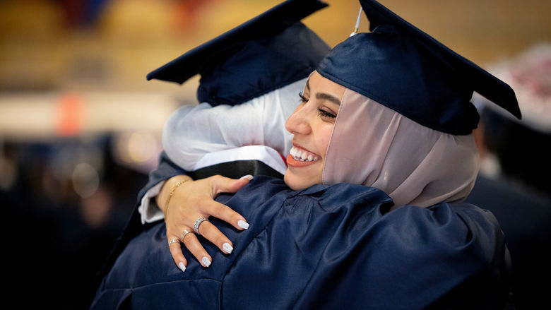 two students hugging in their caps and gowns