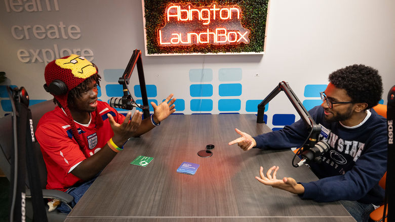Two students during their podcast at a table with mics