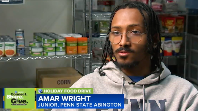 man sitting with cans of food behind him