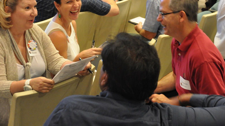 Faculty members sit in small groups discussing and laughing