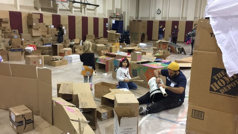 Photo of gymnasium filled with cardboard boxes and children playing 