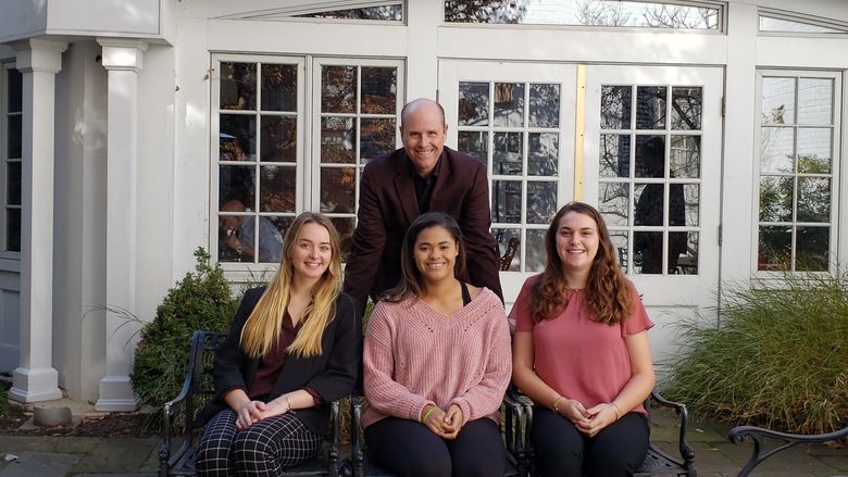 Three students and Paul Perreault in front of the Nittany Lion Inn