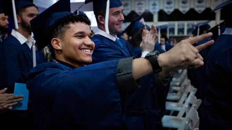 man in cap and gown pointing
