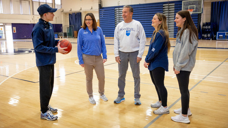 Five people standing on a basketball court