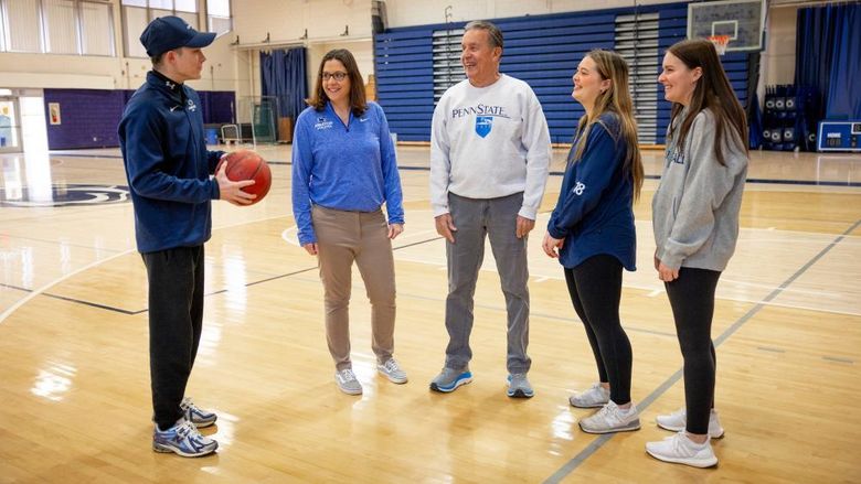 Five people standing on a basketball court
