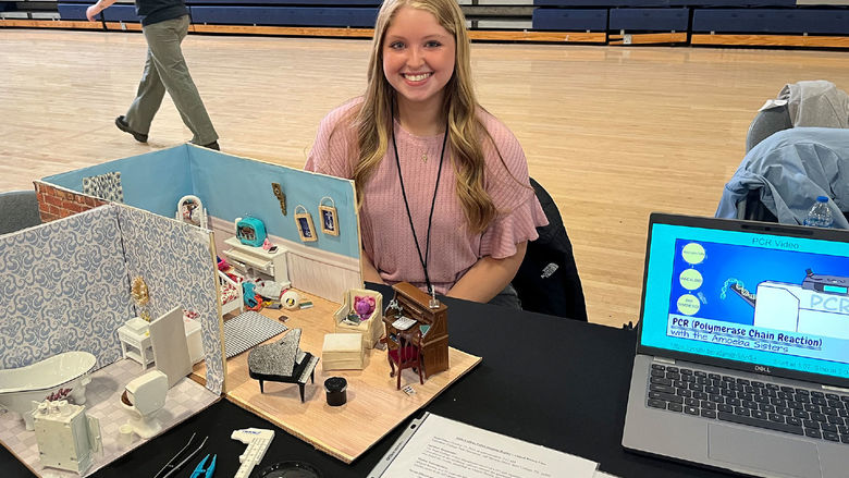 Young woman sitting behind  a crime scene investigation model