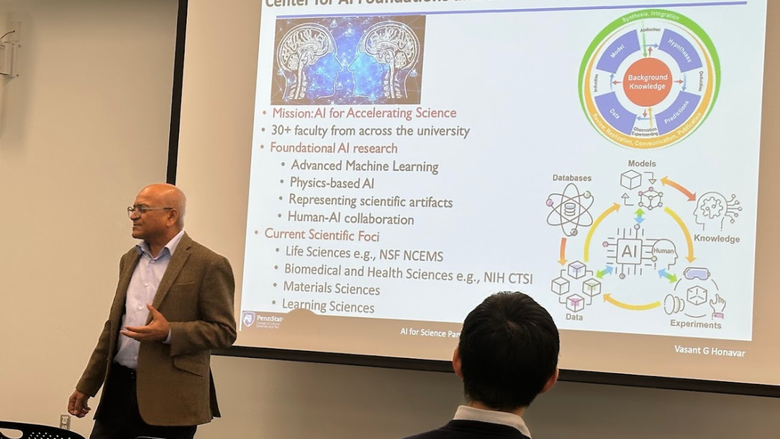 Vasant Honavar, professor in the College of Information Sciences and Technology, stands before a screen presenting his current research focuses during the AI for Science panel.