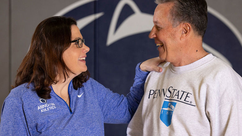 Woman and man talking in front of Penn State athletics logo