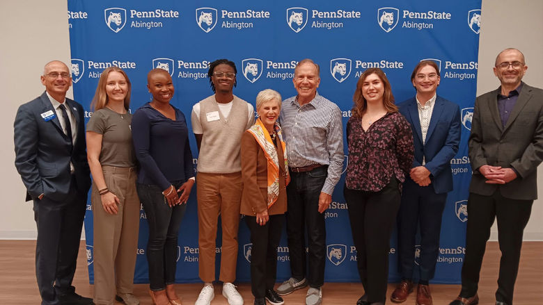 Group of people standing in front of a Penn State Abington banner