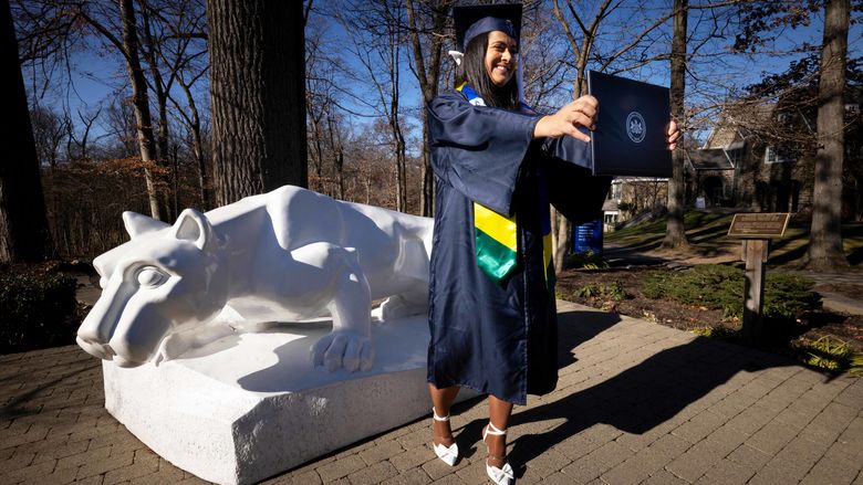 Student holding diploma in front of Lion Shrine 