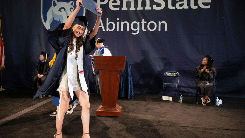 student holding her diploma in the air