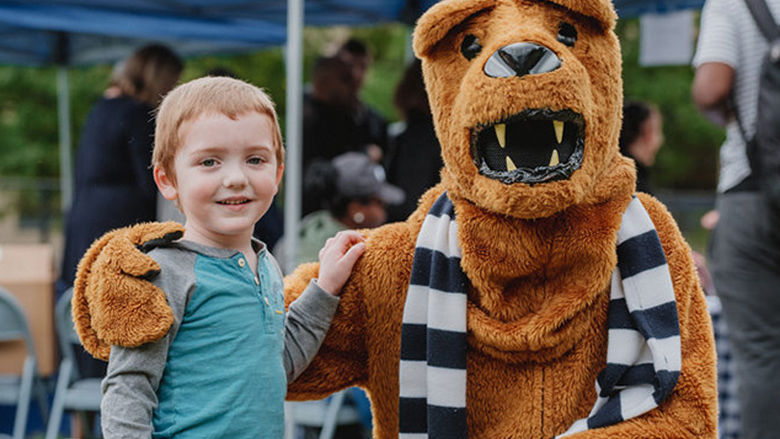 child posing with nittany lion