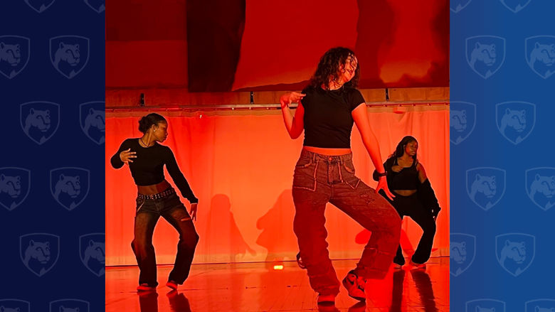Three women dance in orange light