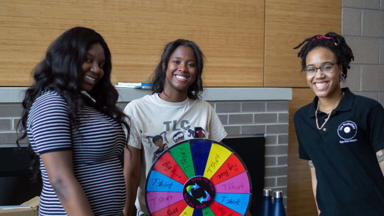 students smiling for photo with spinning wheel